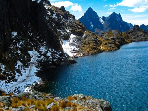 Overlooking a lake in the Lares valley which is surrounded by snow kissed cliffs