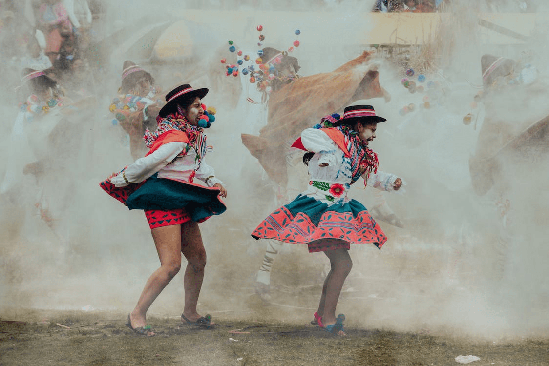Several people dressed in traditional attire are dancing at a festival.