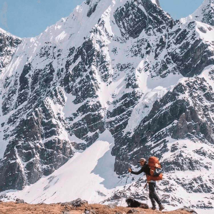 snow capped mountain A hiker going along a mountain with snow-capped peaks.