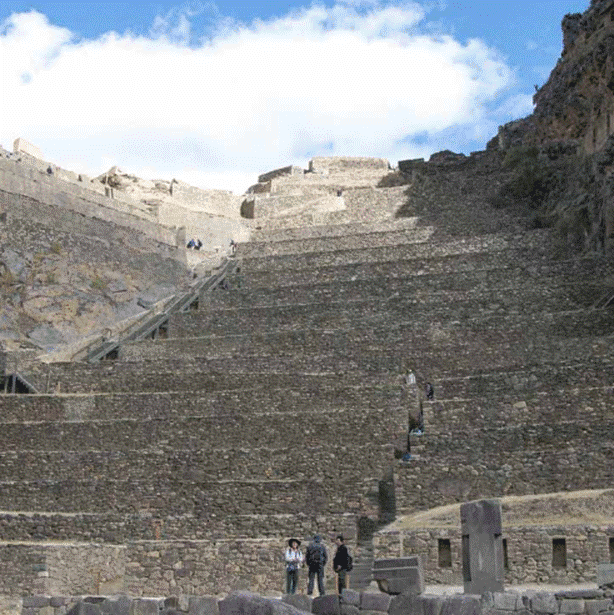 Tourists explore the towering stone terraces and steep staircases of Machu Picchu, a historic Incan citadel nestled in the Andes Mountains of Peru.