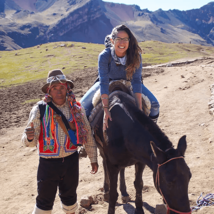 a female tourist on a horseback riding to Rainbow Mountain 