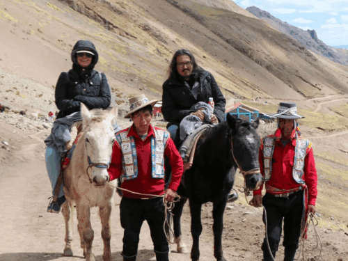 tourists on a tour of the Rainbow Mountain on horses