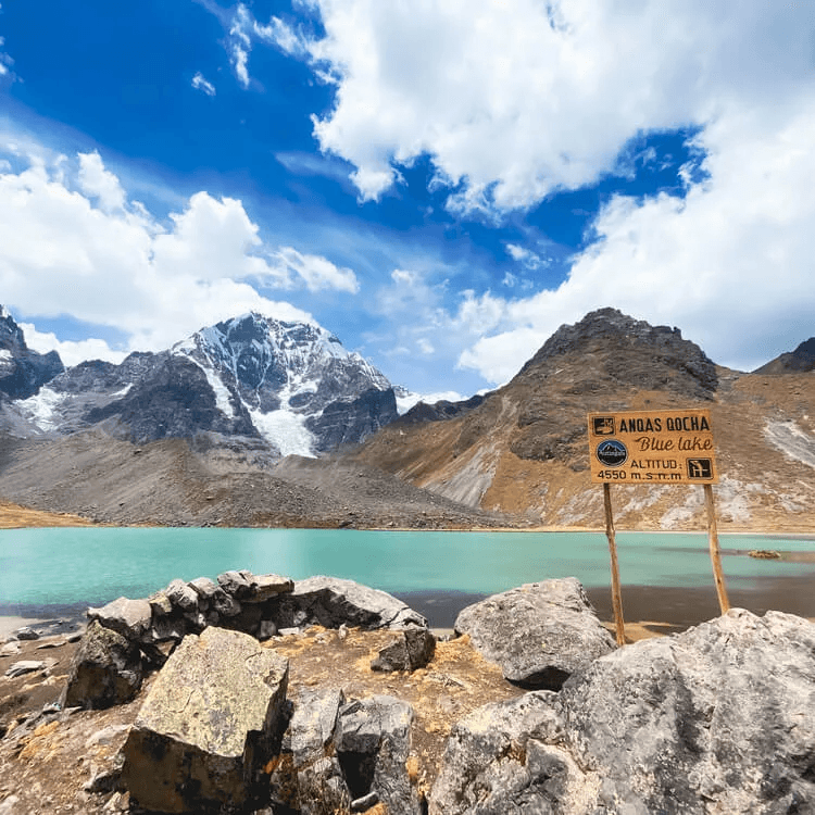 A lake next to a rocky ground with a signpost