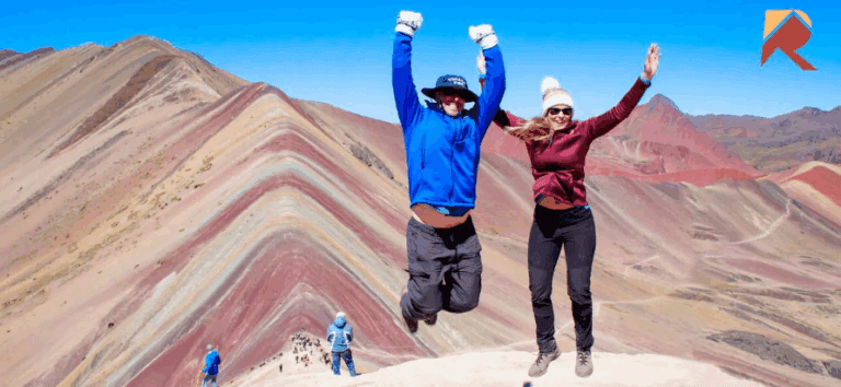 Two people jumping up in the Rainbow Mountains.