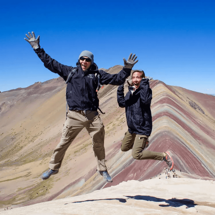 Two people posing for a picture in front of a mountain