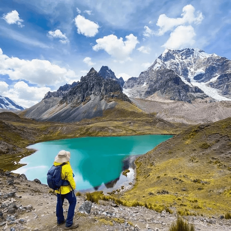 A person standing in front of a lake and mountains