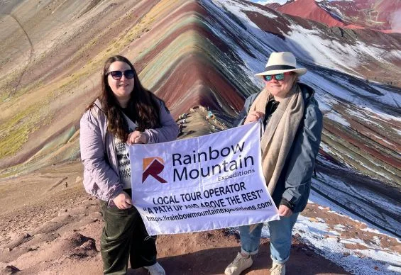  tourists posing with a ‘Rainbow Mountain’ banner 