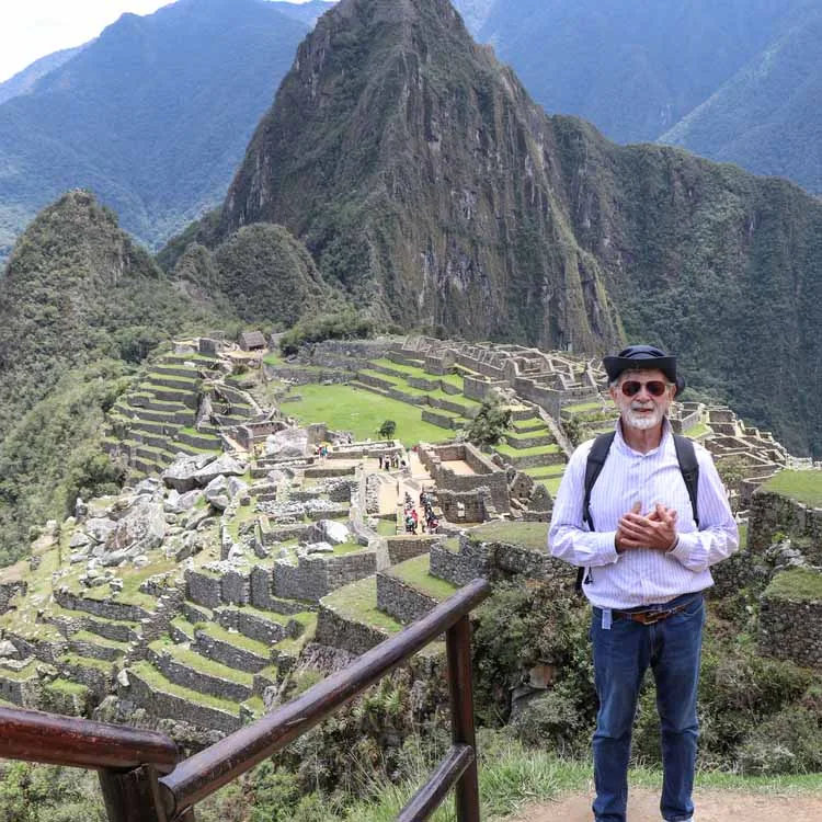 a man posing in front of Machu Picchu