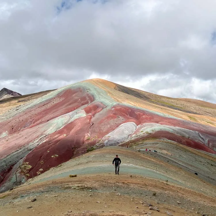 a man walking towards the Rainbow Mountain 