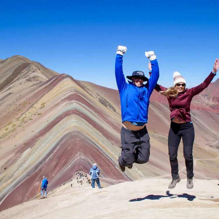 a couple jumping while enjoying the Rainbow Mountain tour