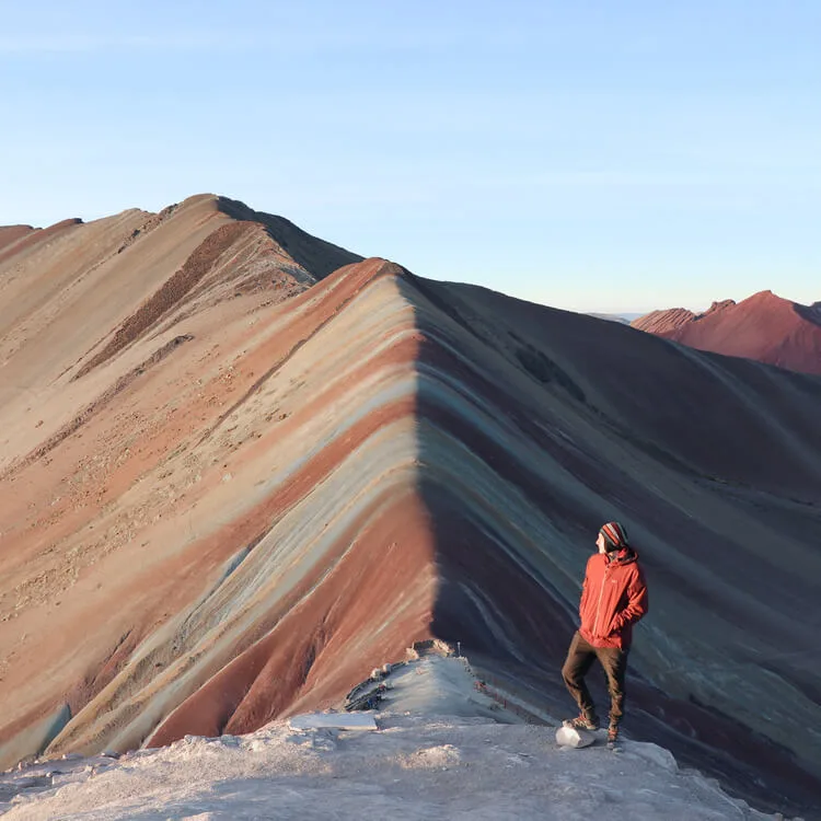 a man posing in front of the Rainbow Mountain