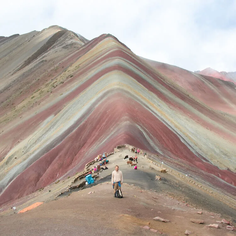 a person standing in the center of one of the mountain peaks with other tourists around