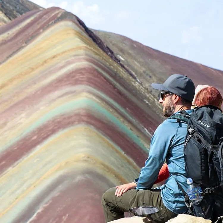 a man sitting in front of the Rainbow Mountain 