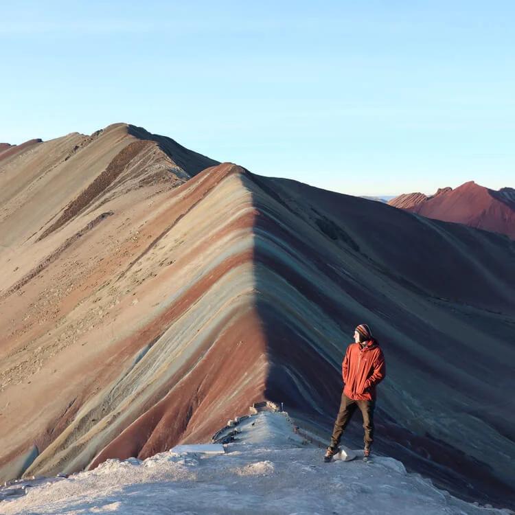 a person posing at the Rainbow Mountains during sunset