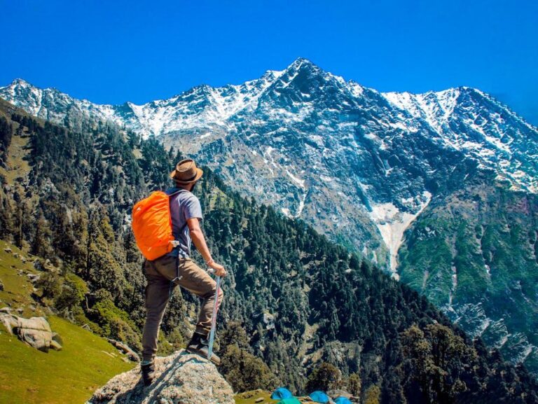 A person trekking with a large orange colored bag