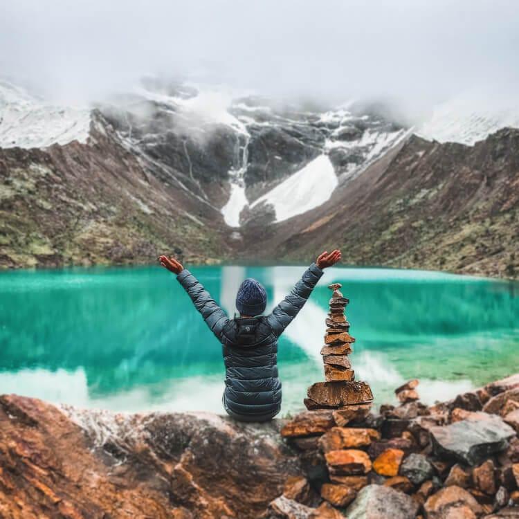 a person with their hands up in front of a lake