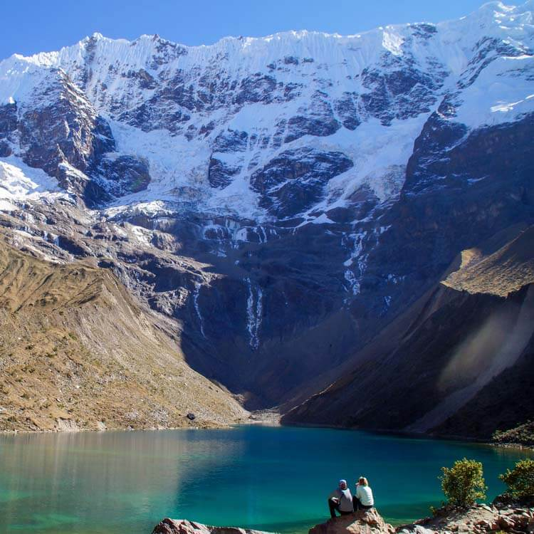 two people sitting on a rock by the Humantay Lake