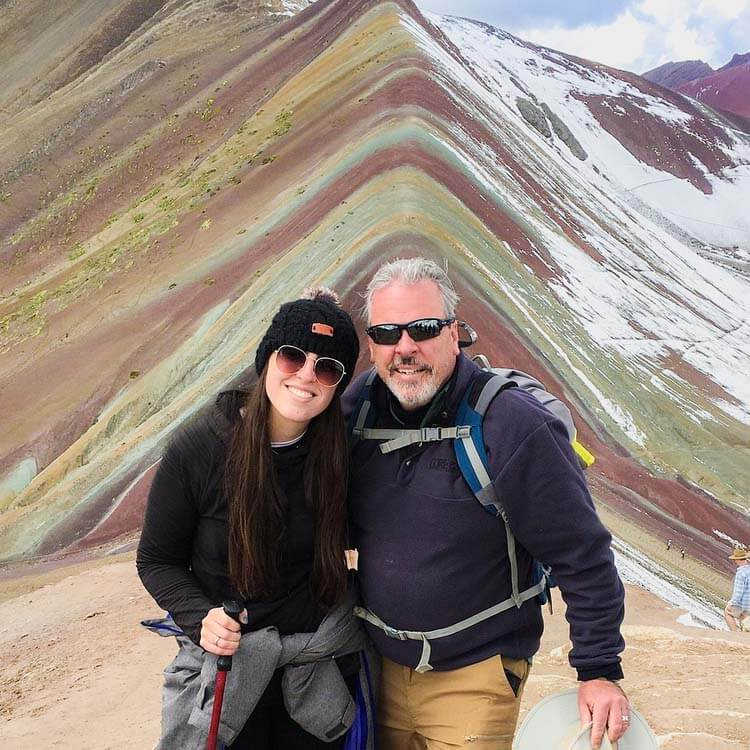 a couple wearing trekking gear posing in the middle of the Rainbow Mountains