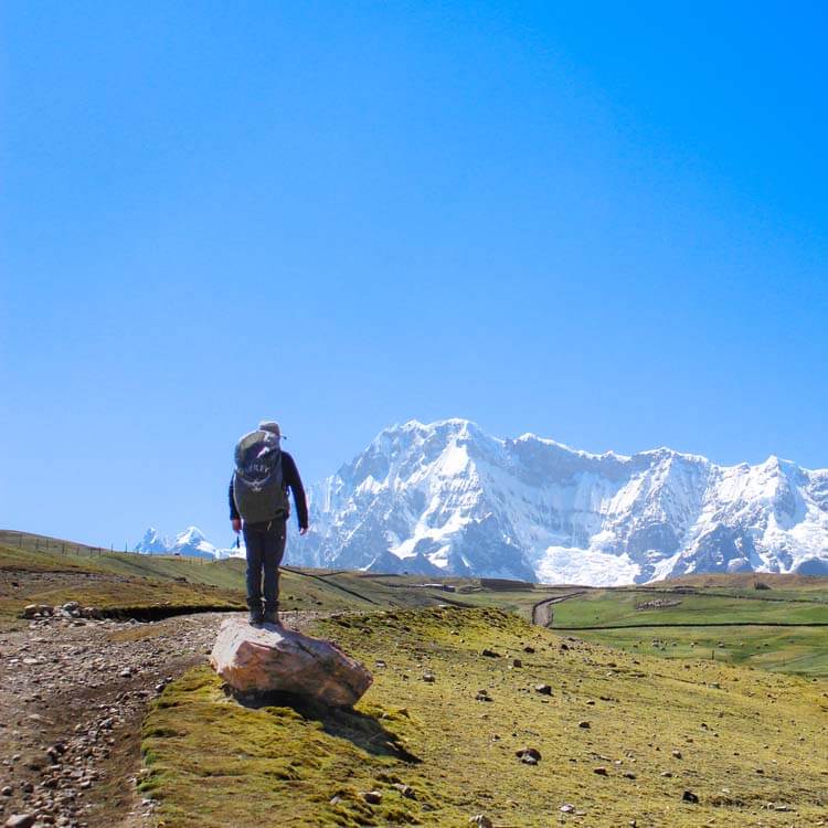 A hiker walking along the uneven Rainbow Mountain trail