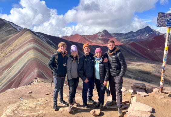 Family wearing warm layers while posing with Rainbow Mountain in the background