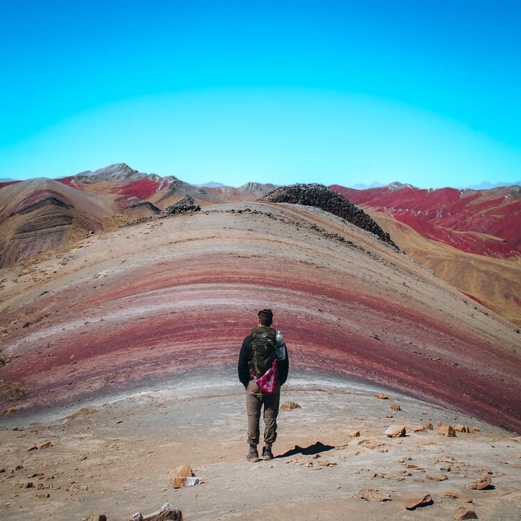 a person standing at the top of the Rainbow Mountain